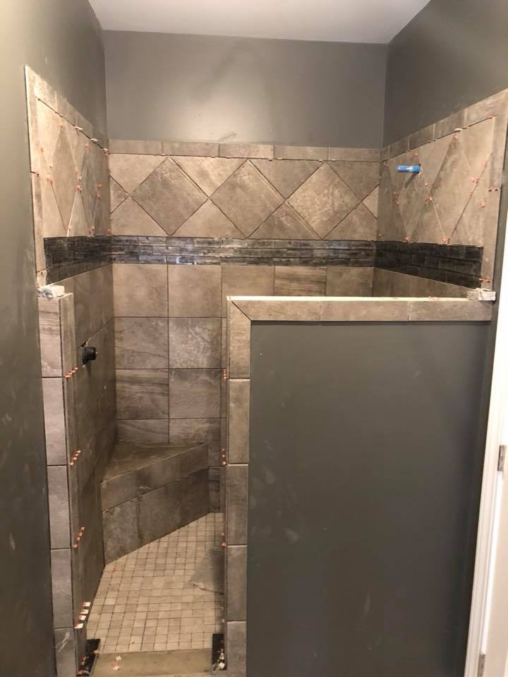 A bathroom with a walk in shower and a gray wall.