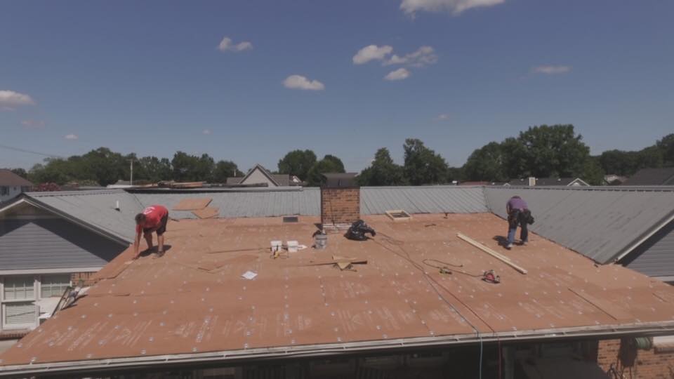 Two men are working on the roof of a building.