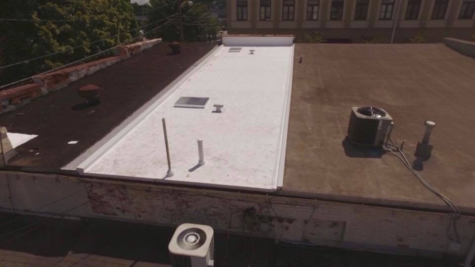 A roof with a white roof and a black air conditioner on it.
