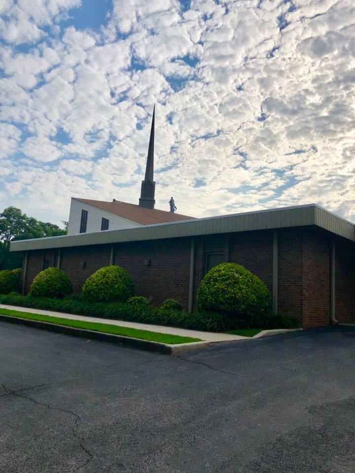 A church with a steeple and a roof on a cloudy day.