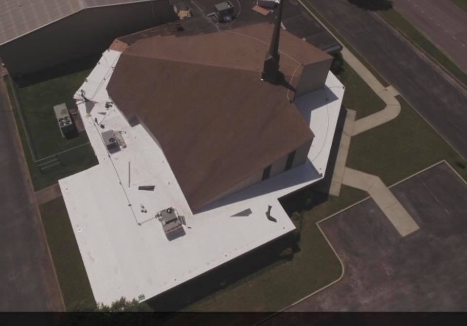 An aerial view of a church with a white roof