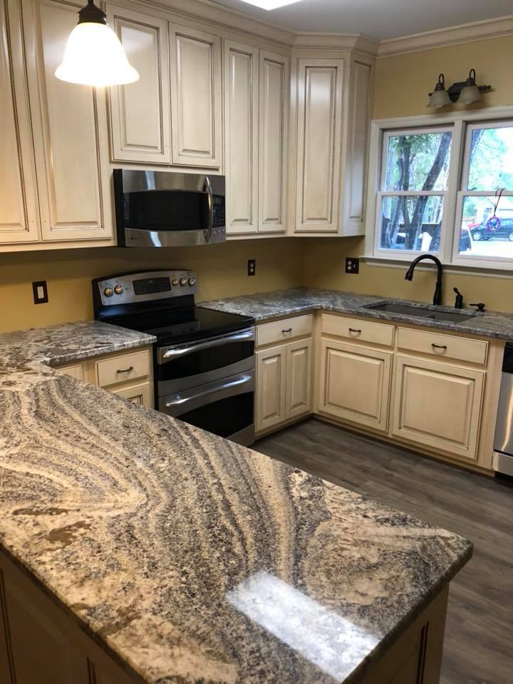 A kitchen with granite counter tops , stainless steel appliances , and white cabinets.