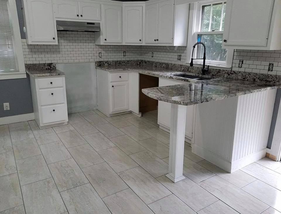 A kitchen with white cabinets and granite counter tops.