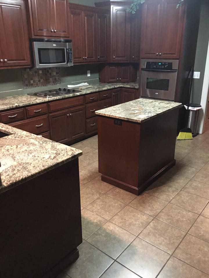 A kitchen with wooden cabinets , granite counter tops , stainless steel appliances and a large island.