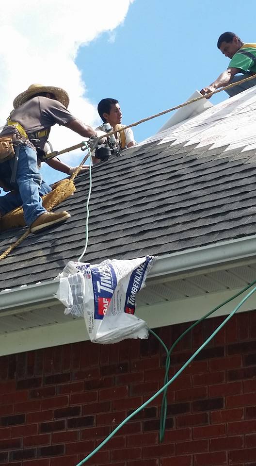 A group of men are working on the roof of a house.