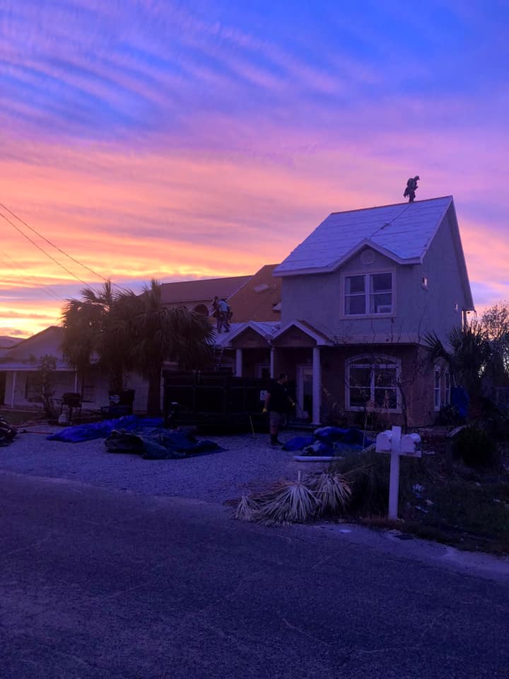 A house with a man on the roof at sunset.