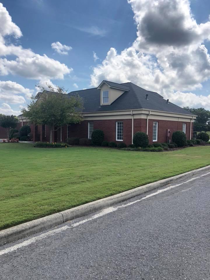A large brick house with a lush green lawn in front of it.