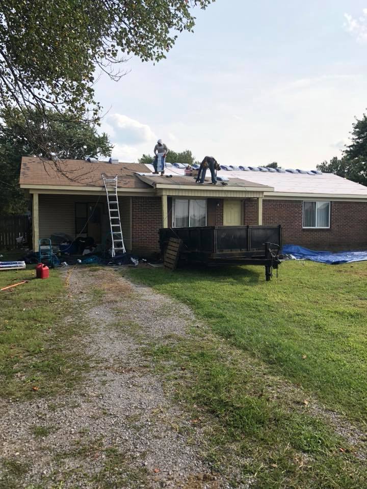 Two men are working on the roof of a house.