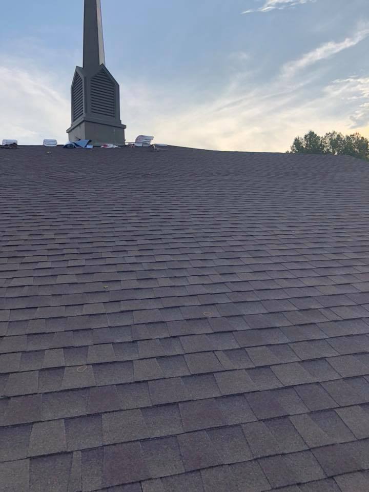 The roof of a building with a clock tower in the background.