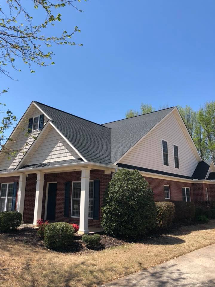 A large brick house with a black roof and white siding.
