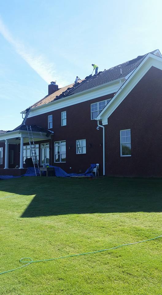 A large red brick house with a large lawn in front of it.