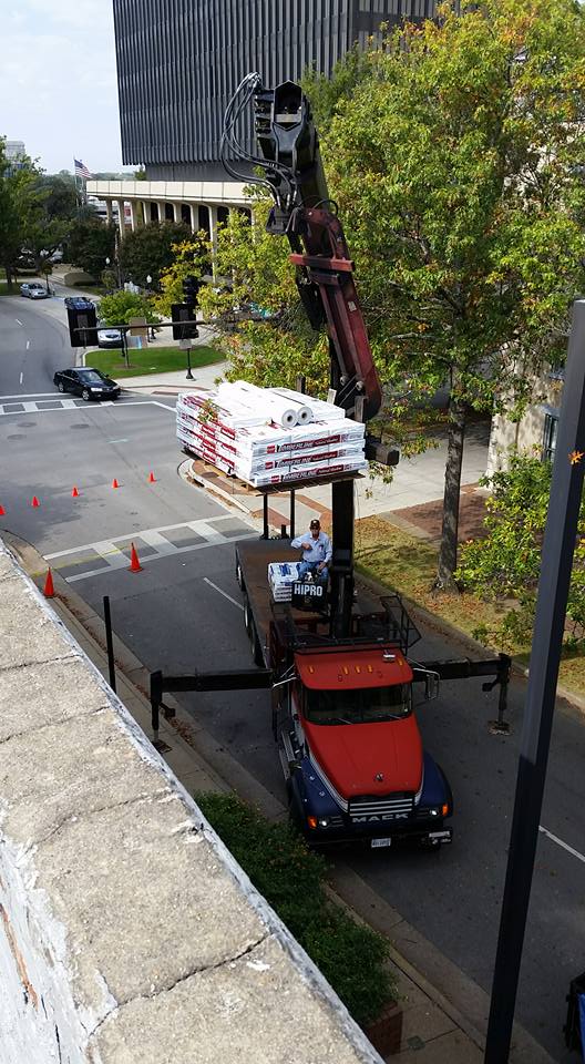 A truck with a crane on top of it is driving down a city street.