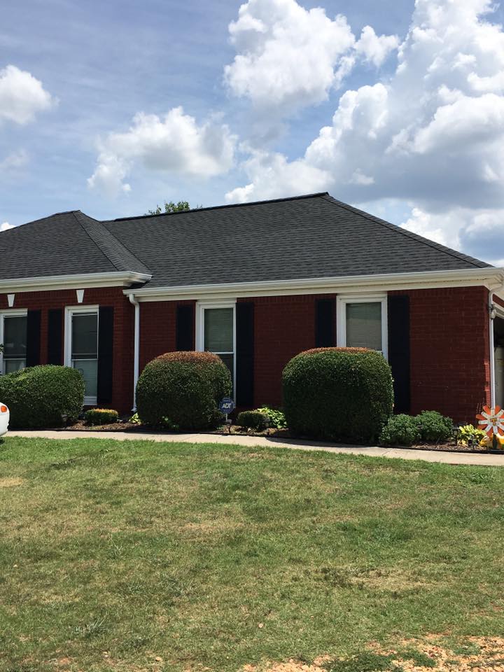 A red brick house with a black roof and black shutters