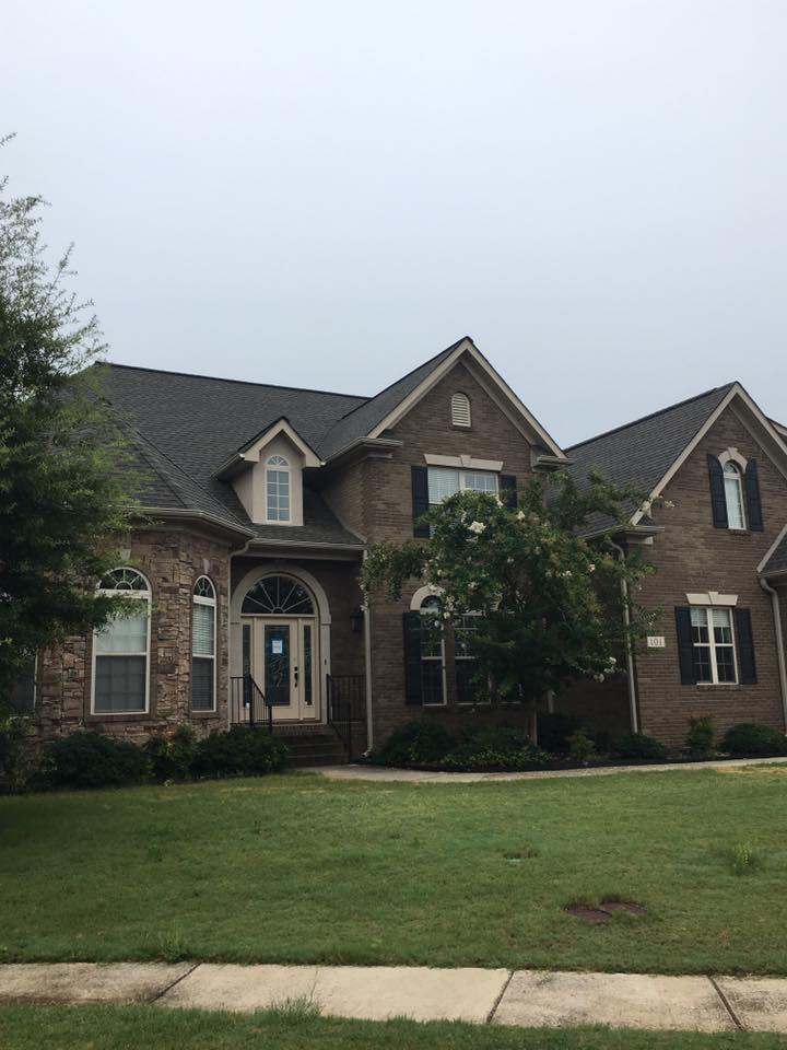 A large brick house with a gray roof and black shutters