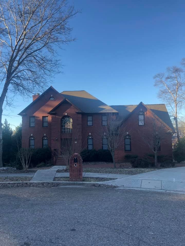 A large brick house with a gray roof and a mailbox in front of it.