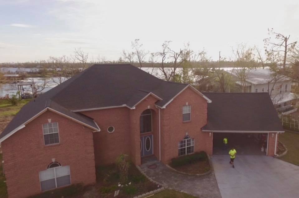 An aerial view of a large brick house with a black roof.