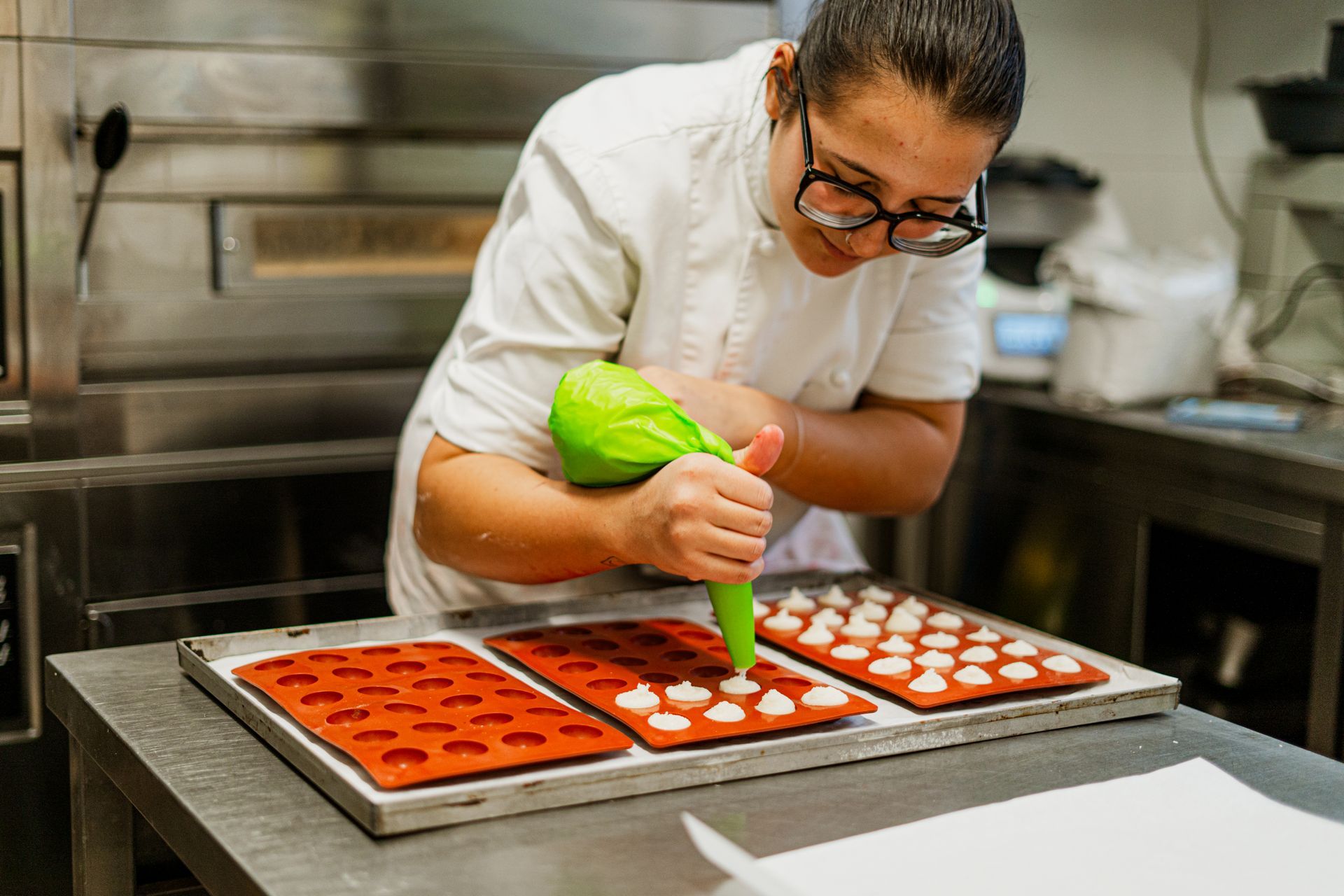 una donna sta decorando un vassoio di cioccolato in una cucina .