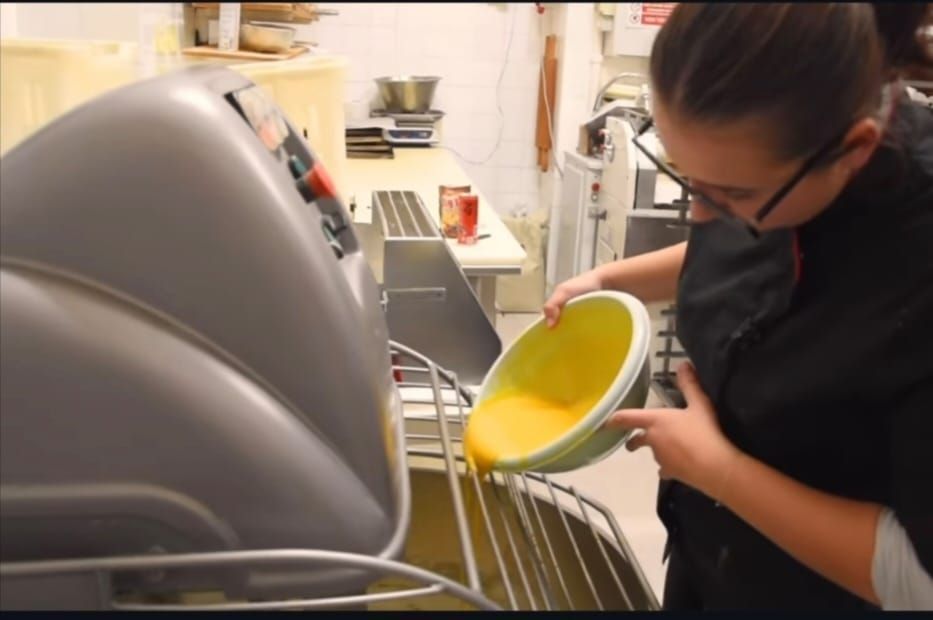 una donna sta decorando un vassoio di cioccolato in una cucina .