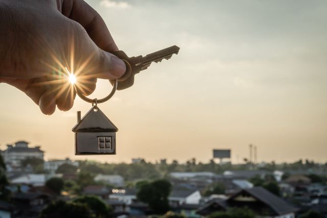 photo of a key being held up to the sky with homes in the background