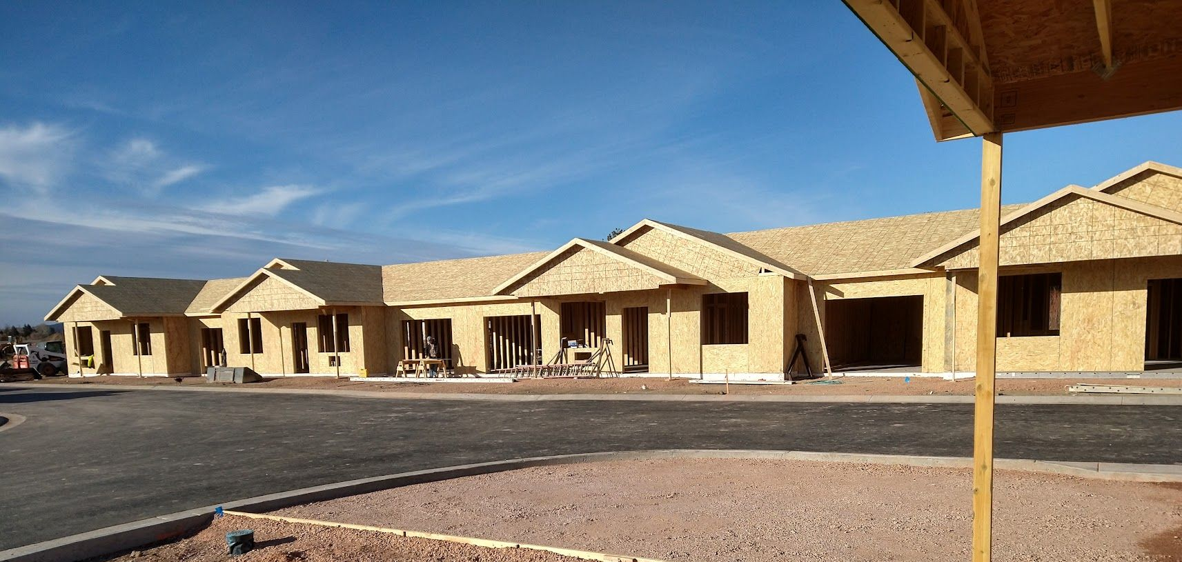 A yellow hard hat is sitting on top of a blueprint next to a model house.