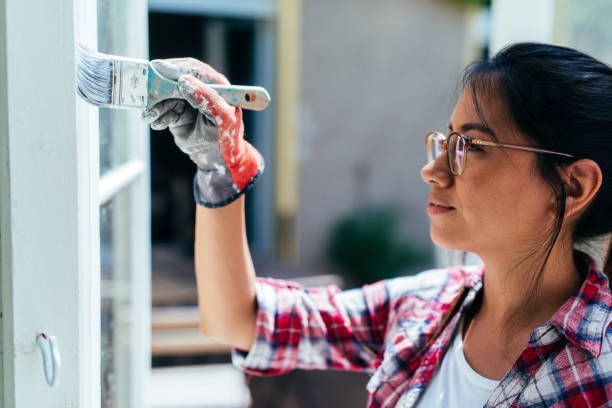Woman painting garden house.