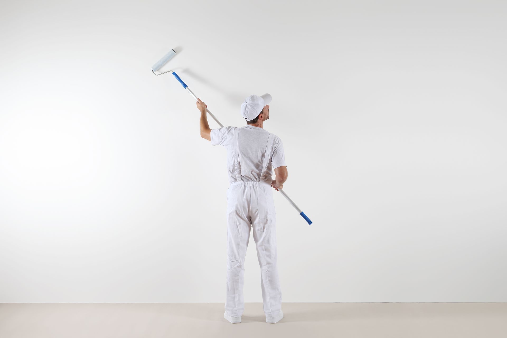 A person in white paint holding a roller | Exterior House Paints in Miami Gardens FL | Associated Pa