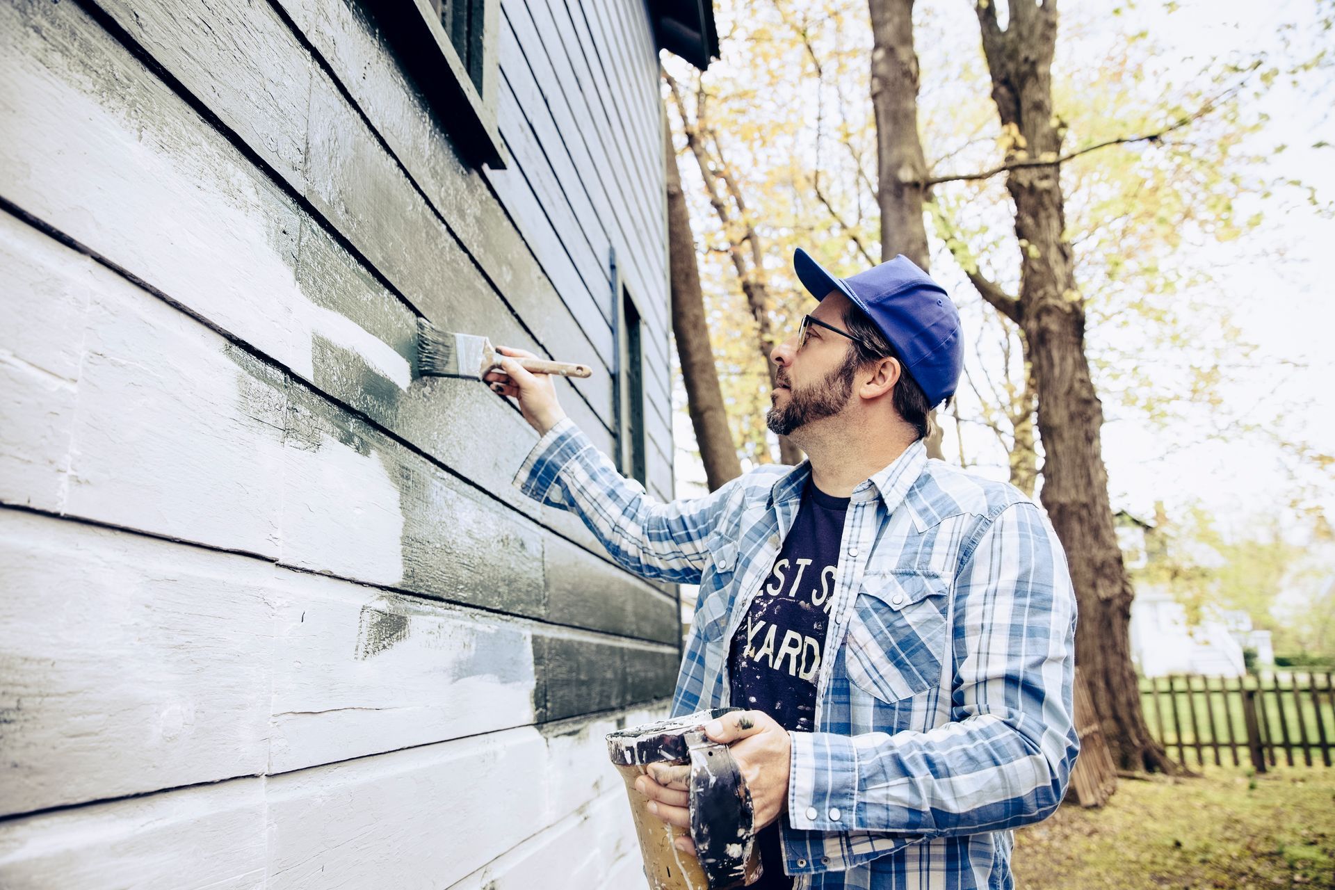 Side view of man painting exterior of home.
