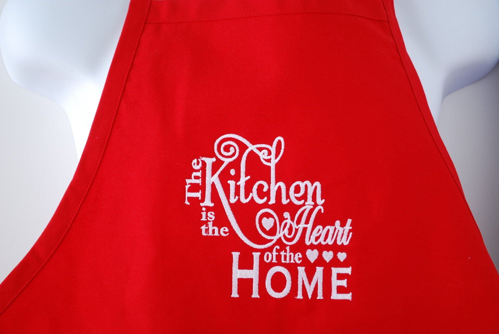 A red apron that says, The kitchen is the heart of the home