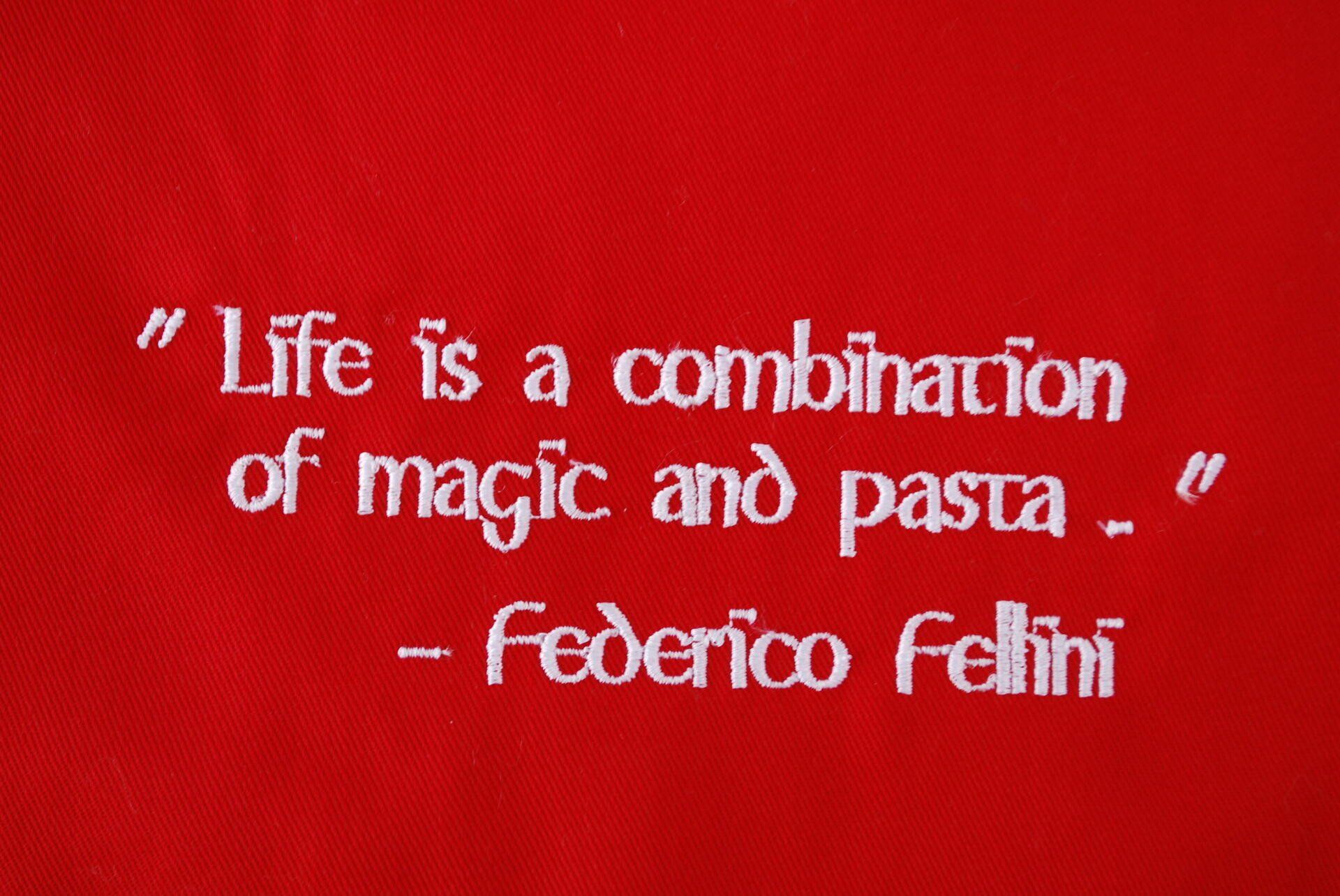 A red apron with a quote embroidered on it