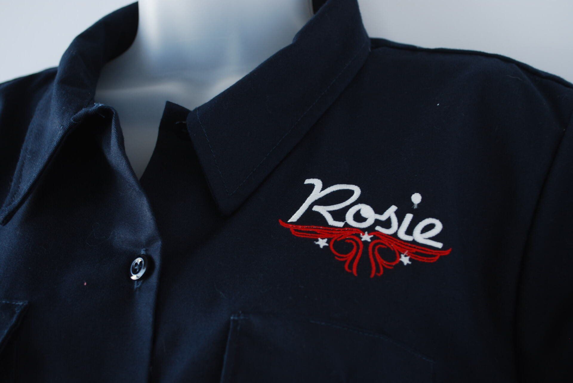 A navy blue shirt with Rosie embroidered on it
