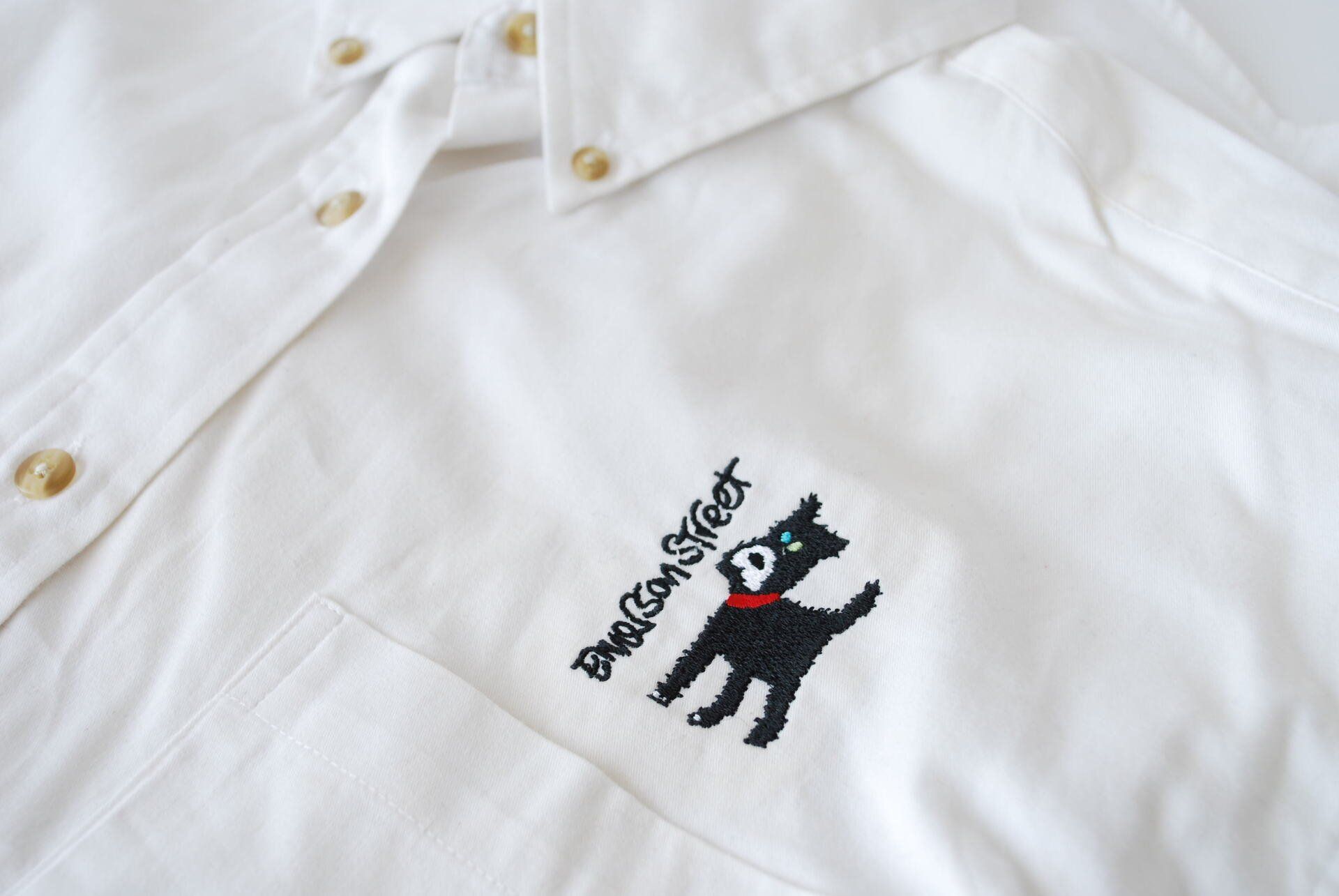 A white shirt with a black dog embroidered on it