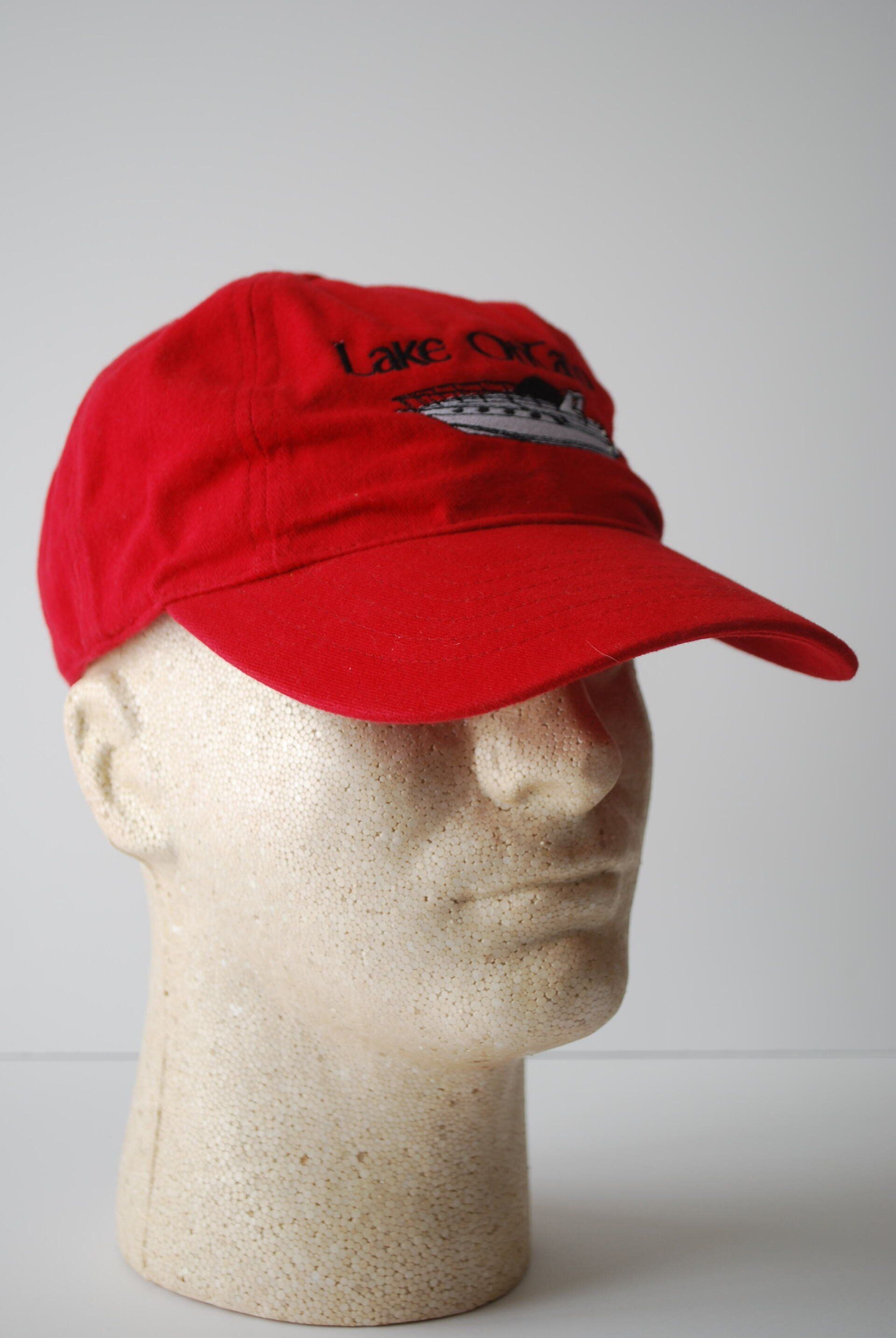 A red baseball cap with a Lake Ontario boat logo on a mannequin head