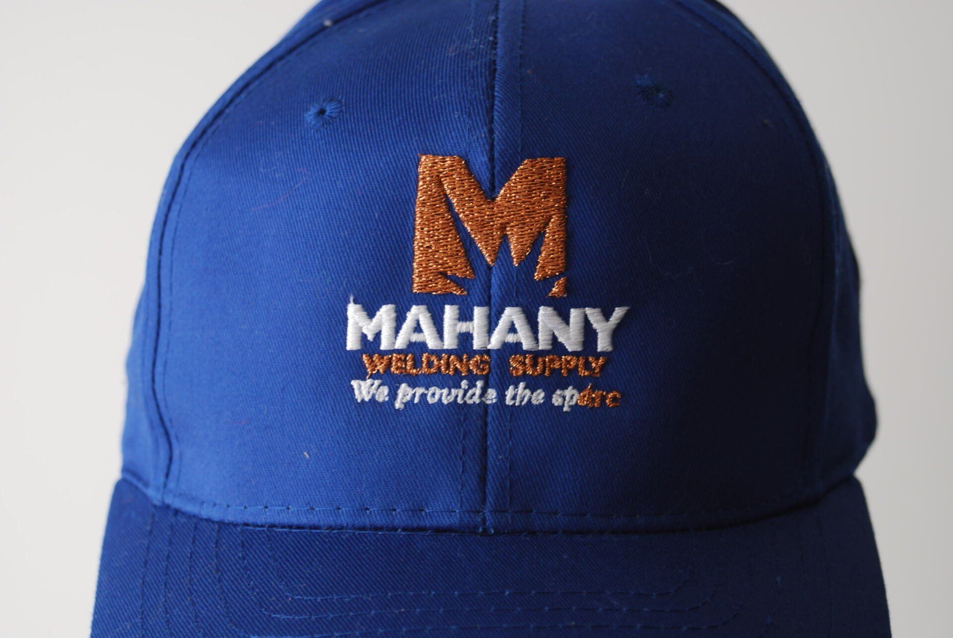 A blue baseball cap with Mahany Welding Supply embroidered on it