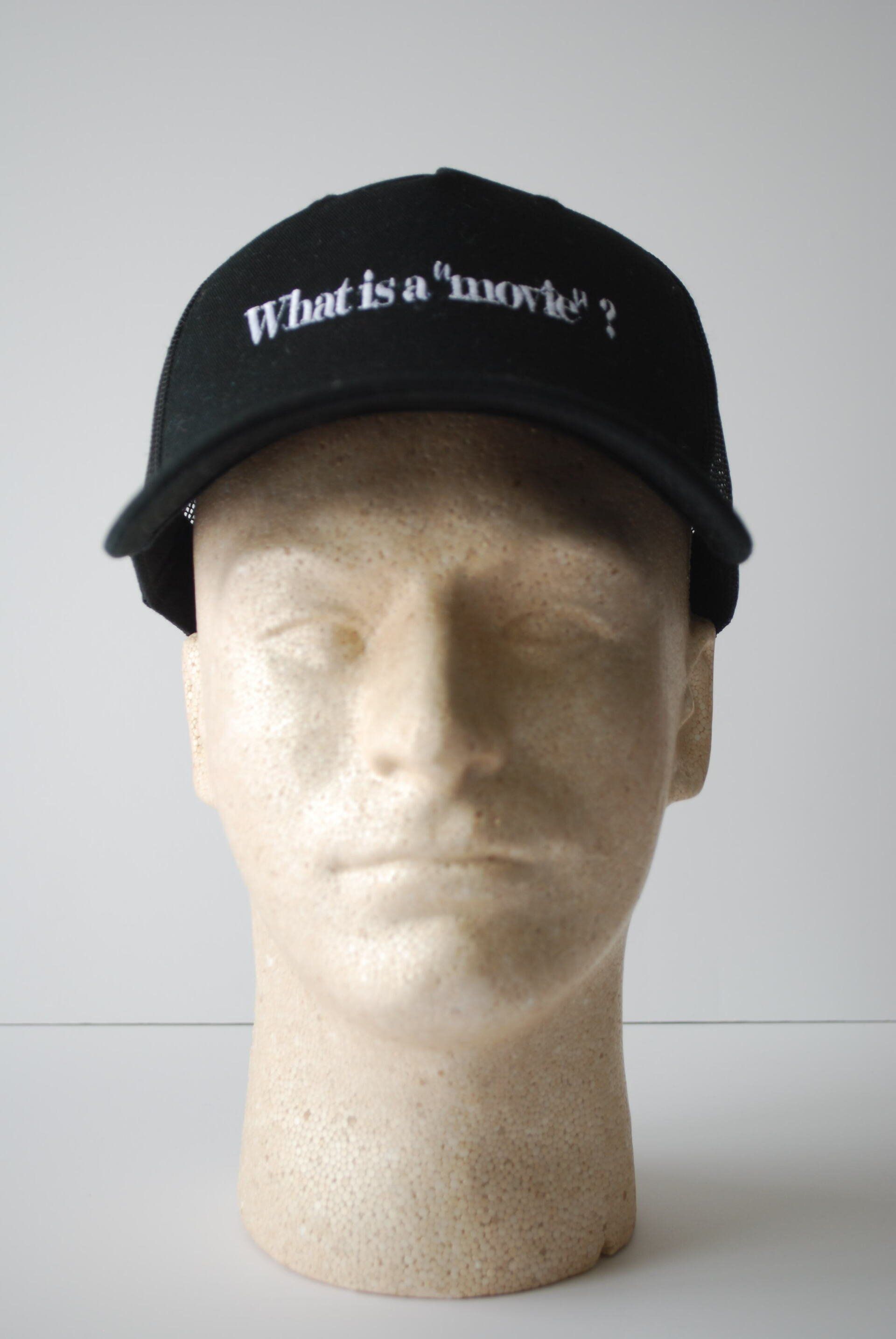 A mannequin head wearing a black hat with a phrase embroidered on it
