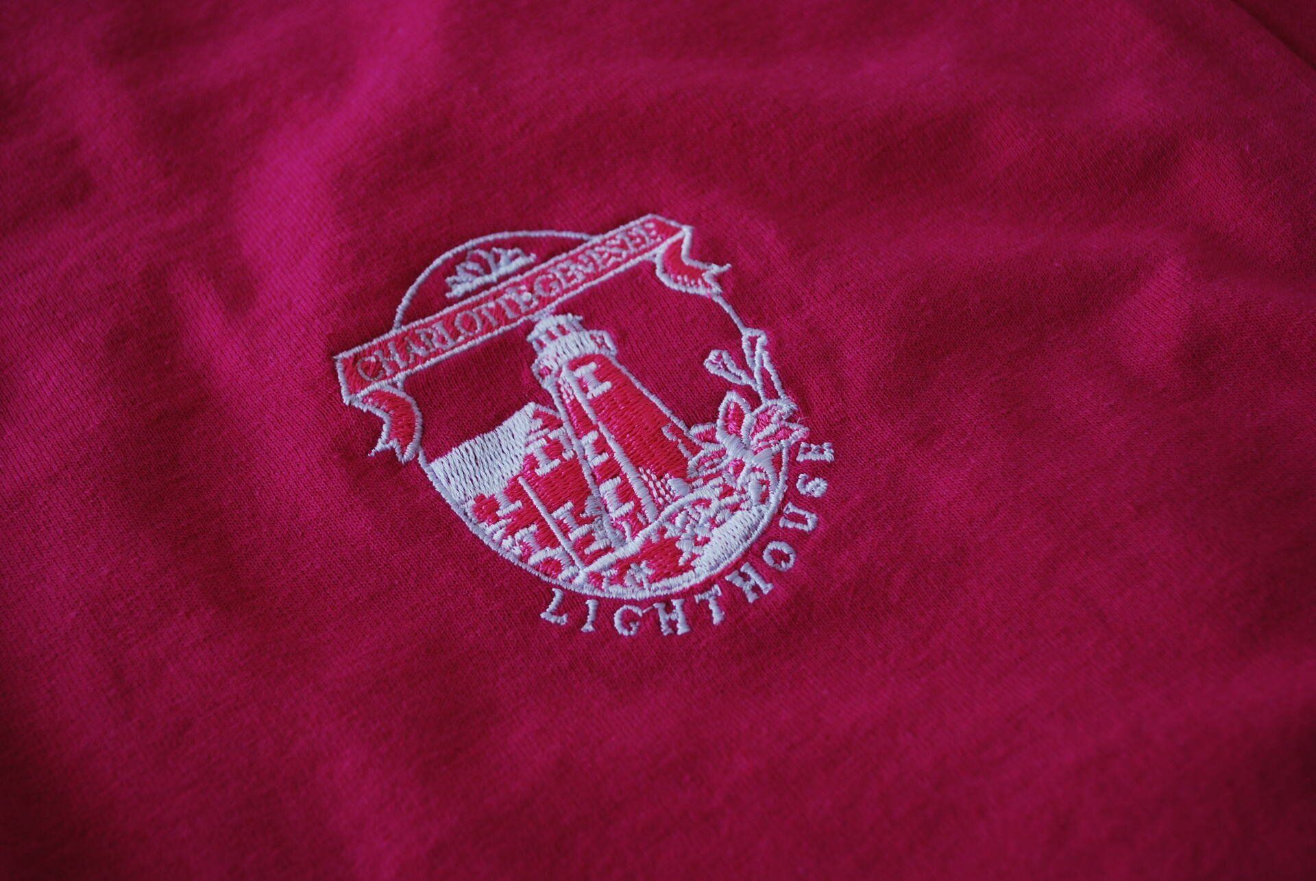 A close up of a pink shirt with a lighthouse embroidered on it