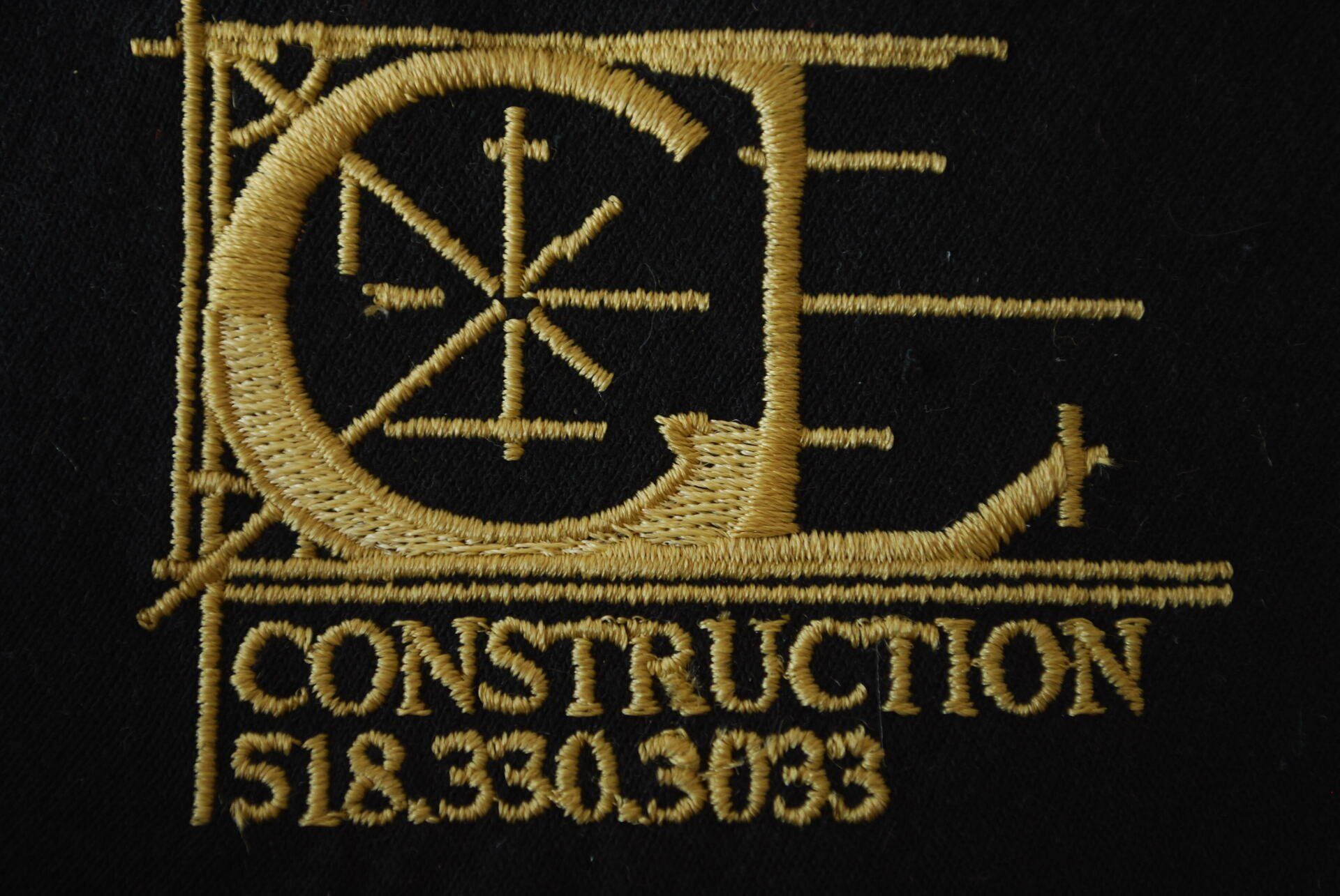 A black and gold embroidered logo on black apparel