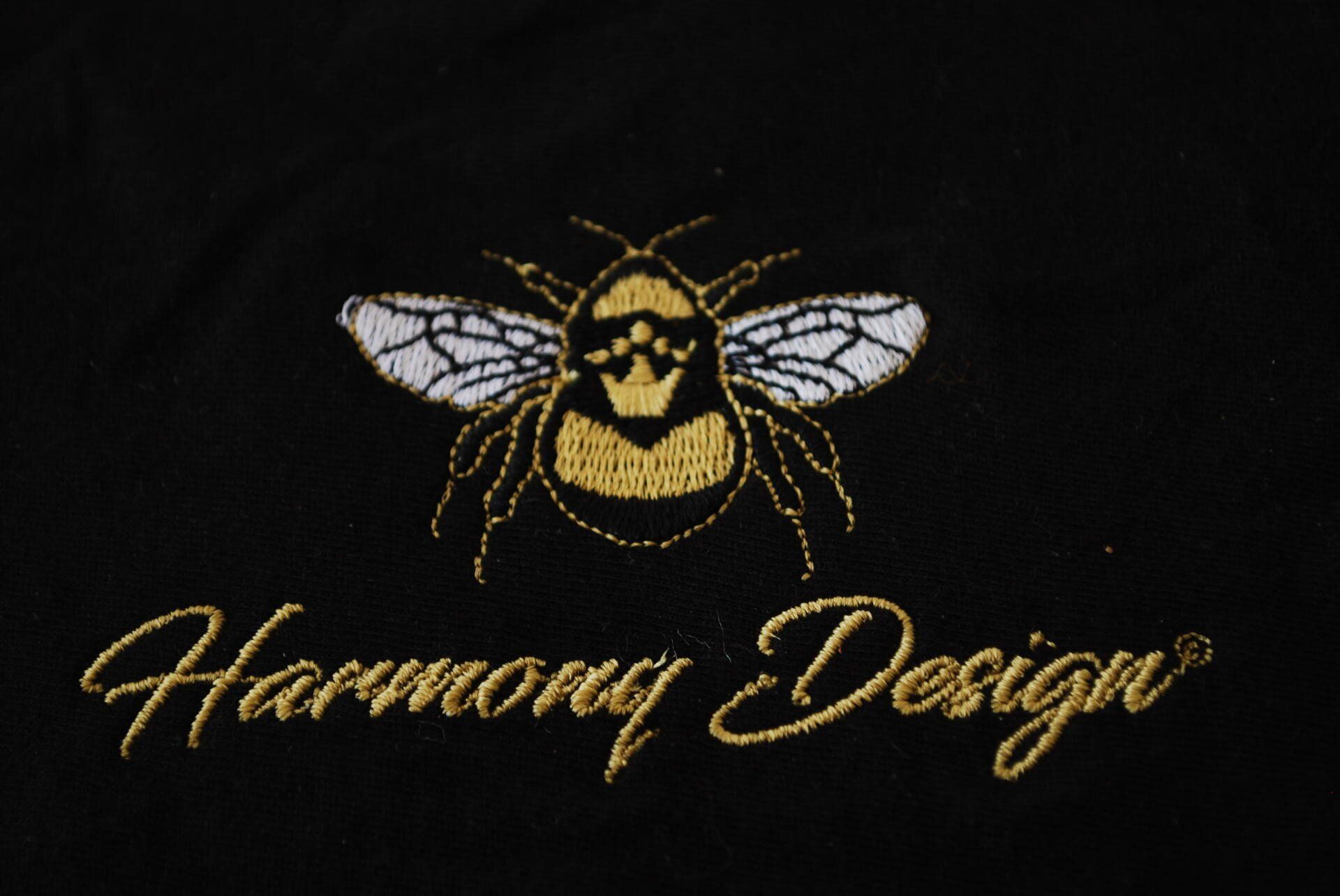 The Harmony Design bee logo embroidered on black apparel