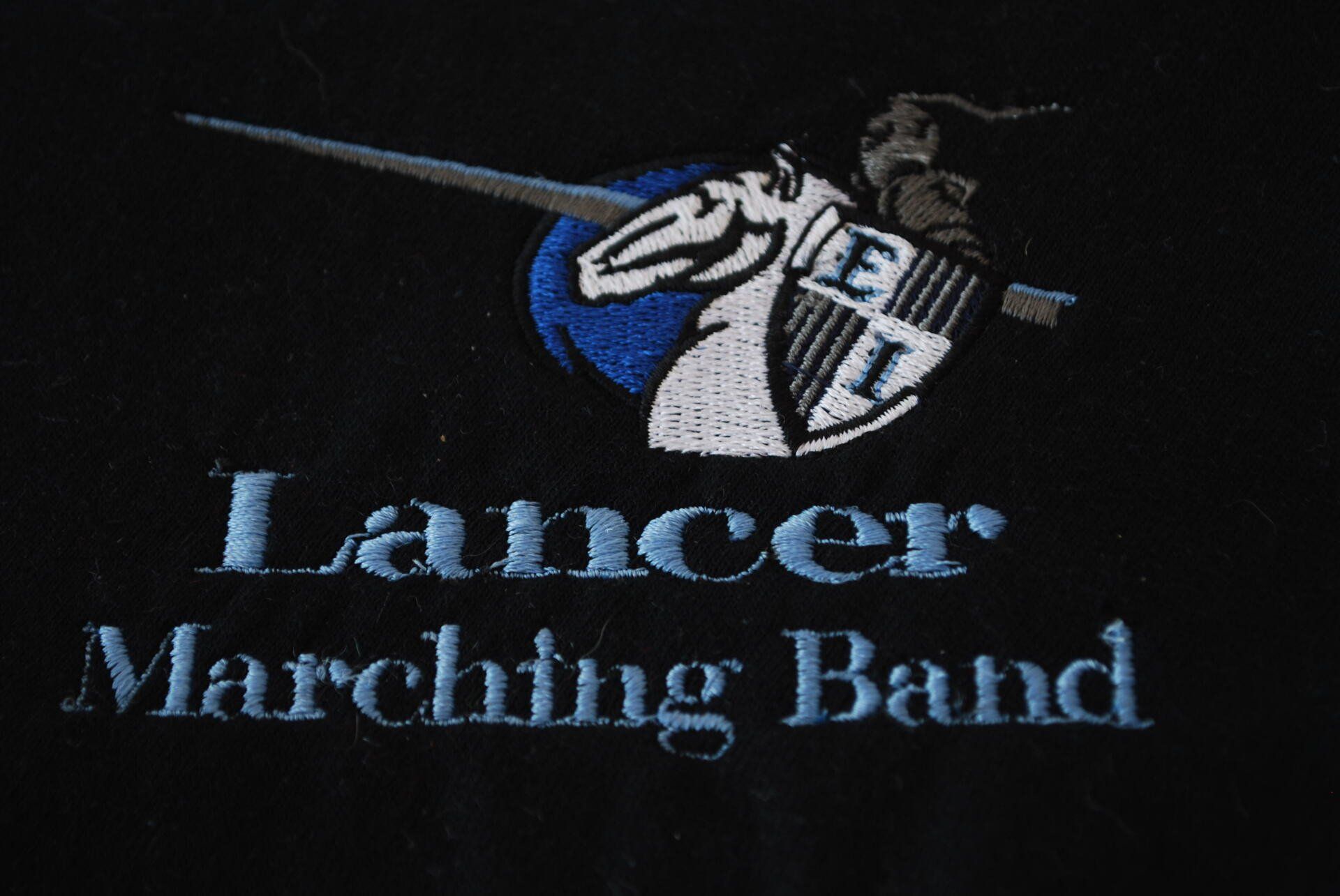 The Lancer Marching Band logo embroidered on black apparel