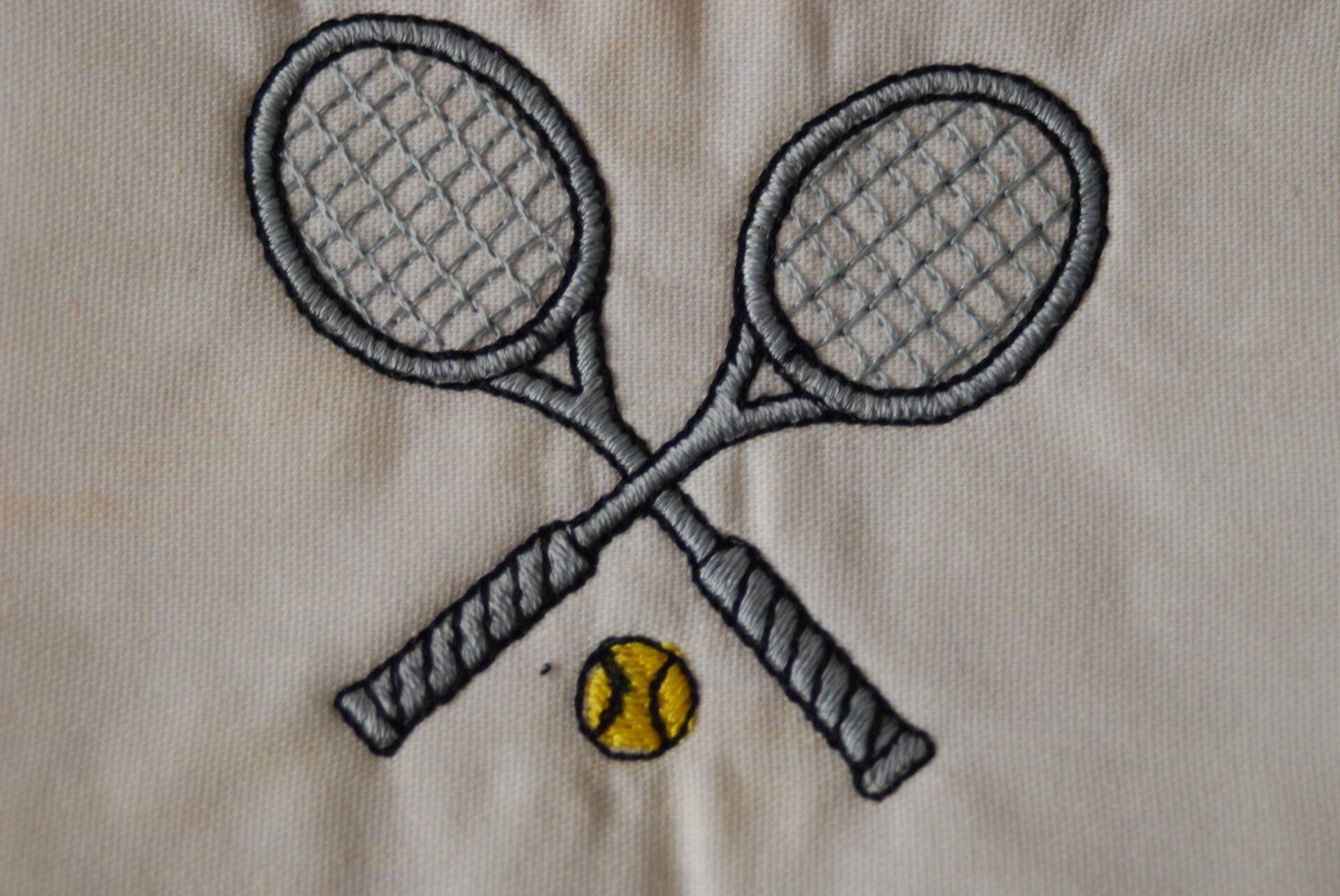 Two tennis rackets and a tennis ball embroidered on white apparel