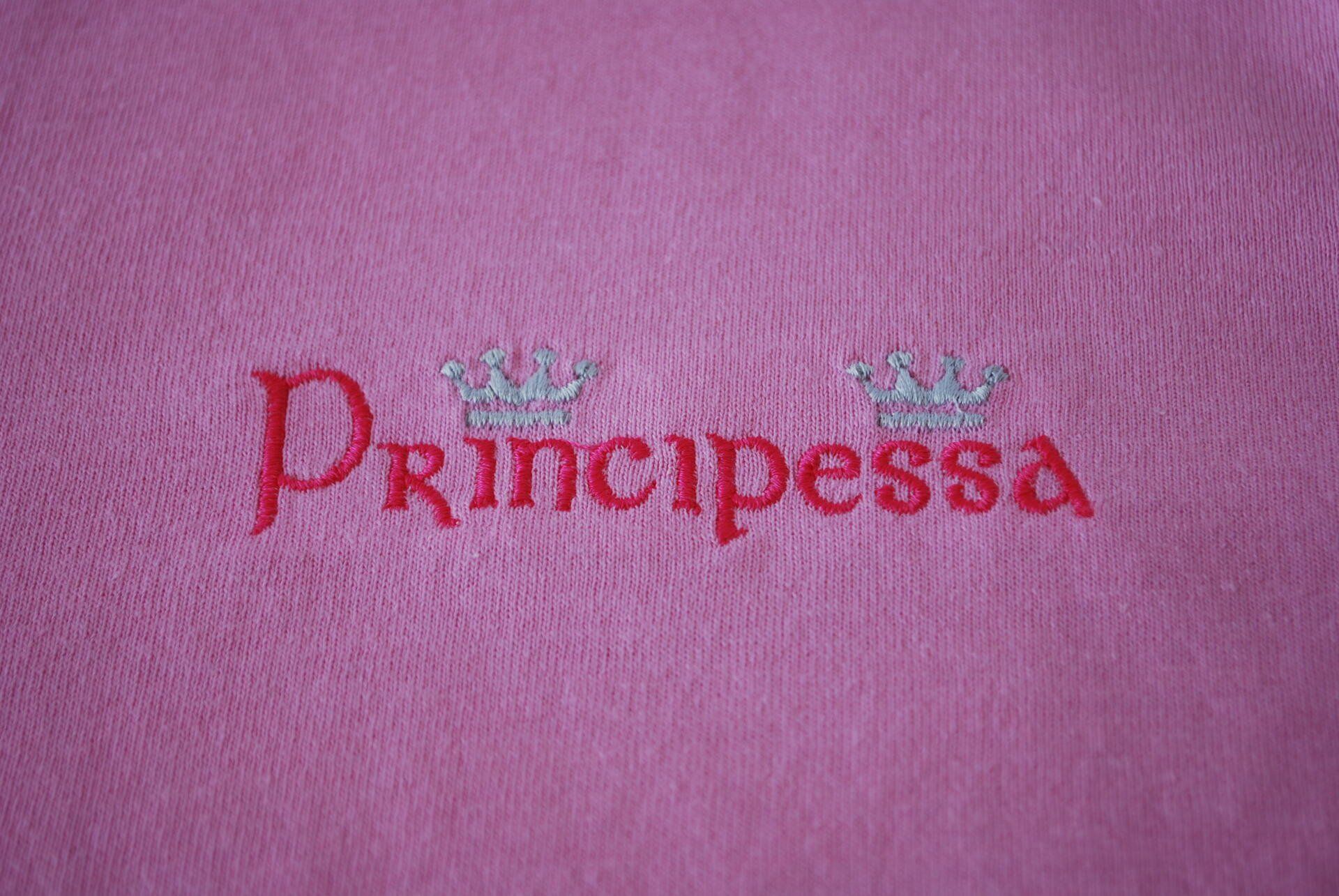 The Italian word Principessa embroidered on pink apparel