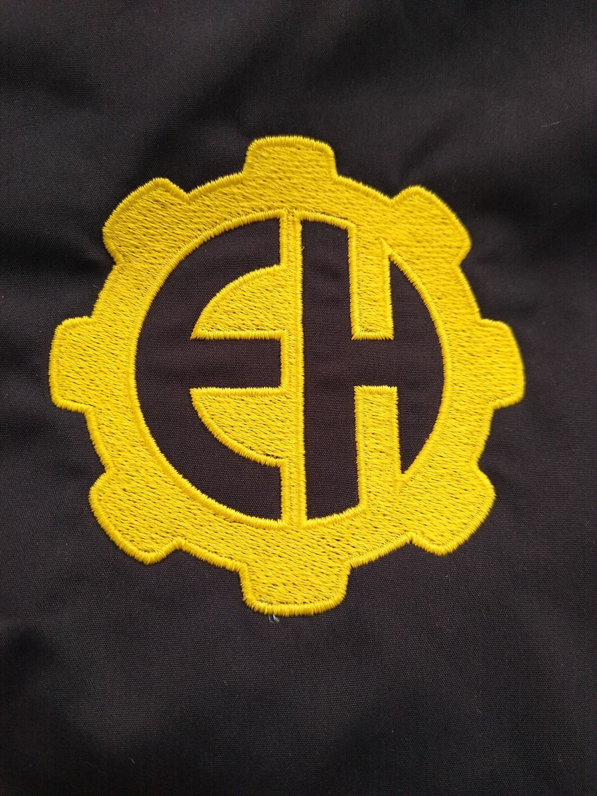 A yellow gear with the letters E H embroidered