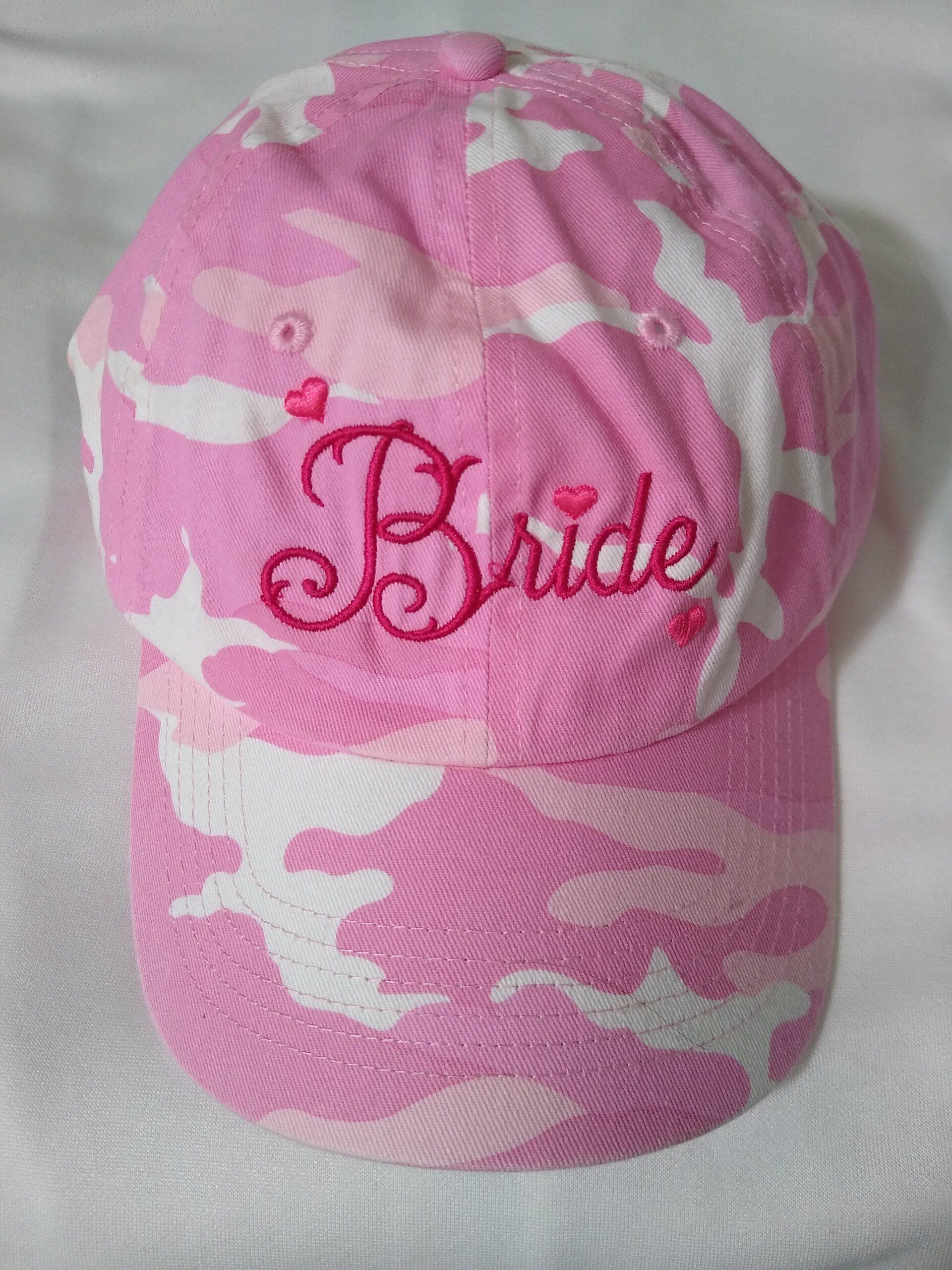 A pink camo hat with the word Bride embroidered on it