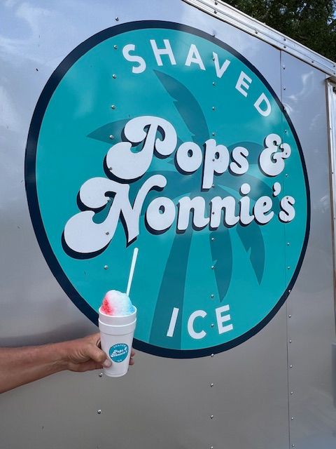A person holding a cup of pops and nonnie 's shaved ice