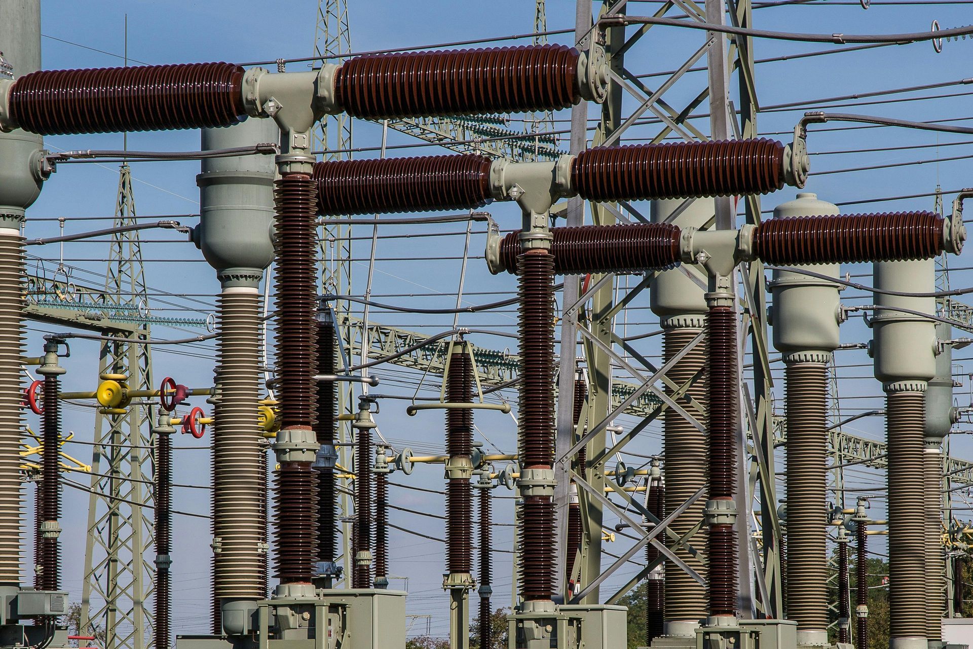 Power substation equipment with brown insulators, wires, and metal framework.