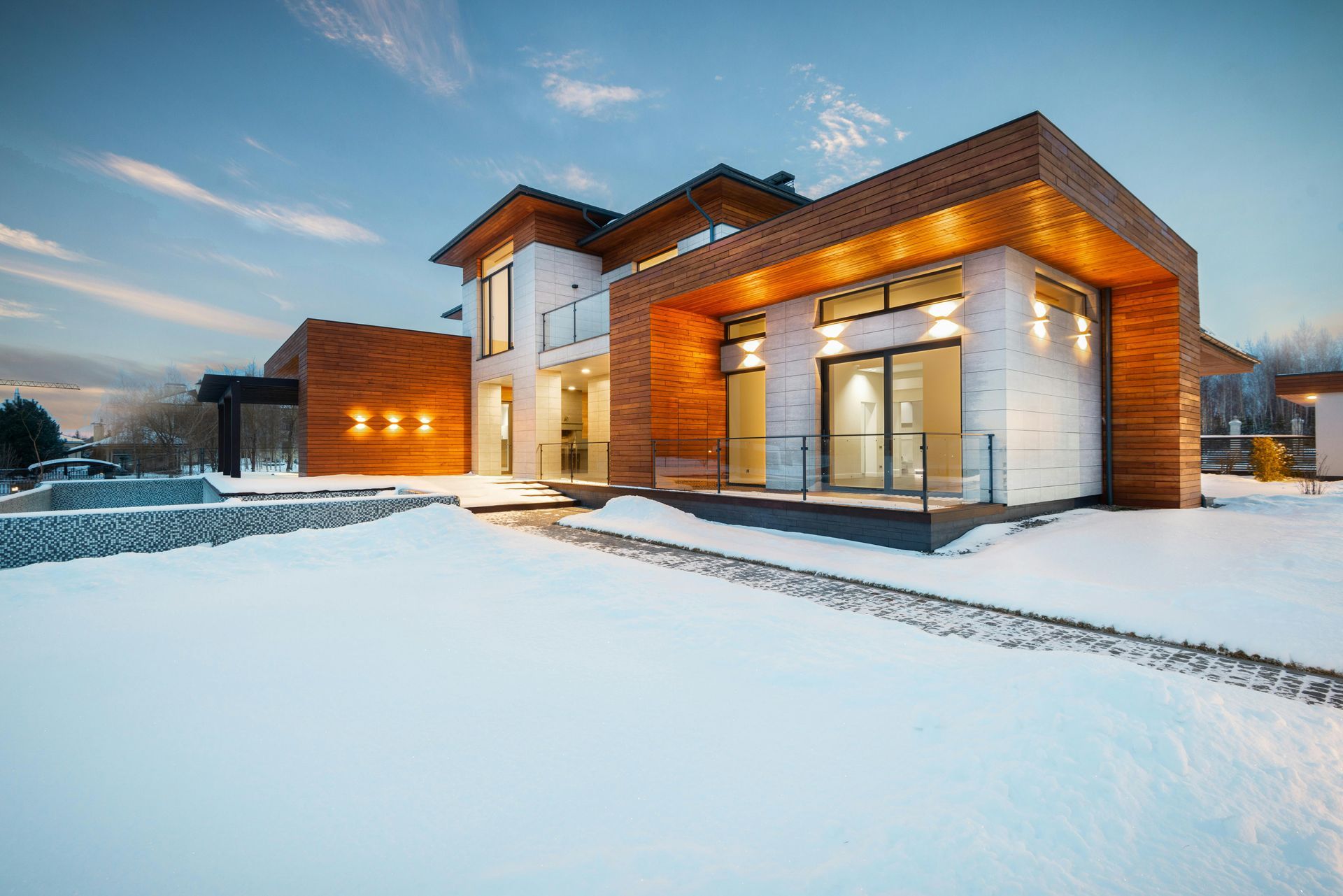 Modern house with wood accents and white brick in a snow-covered landscape.