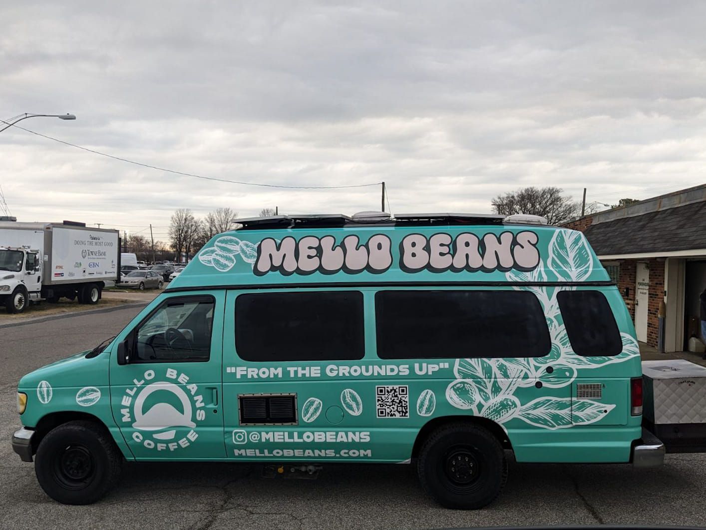 Teal Mello Beans coffee van with logo, parked on street. 