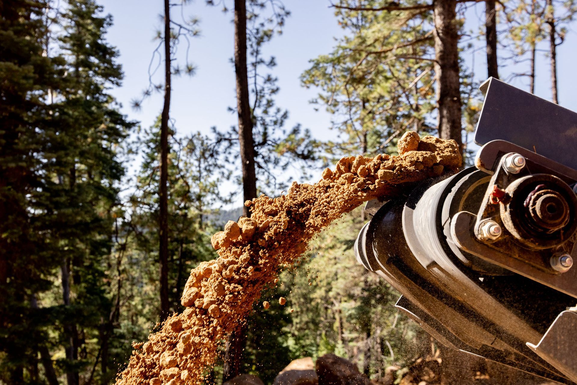 Yellow excavator demolishing a building's roof and upper walls; debris on the ground.