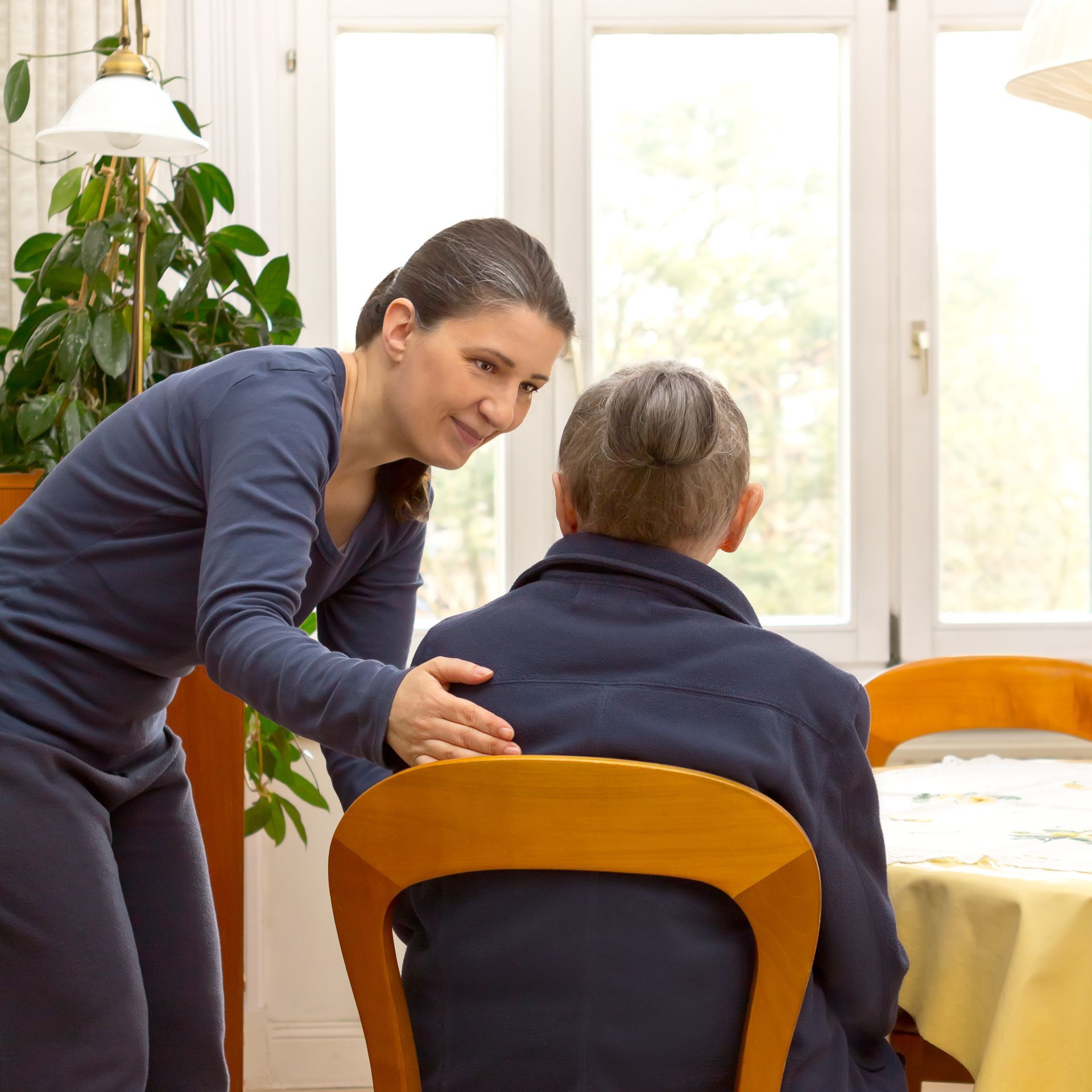 A caregiver is helping a senior woman to sit. A caregiver is helping a senior woman to sit.