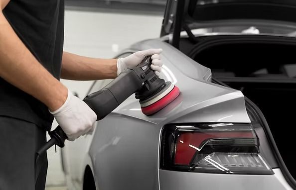 Person using a polishing tool on a silver car in a garage. | Scottsdale Protech