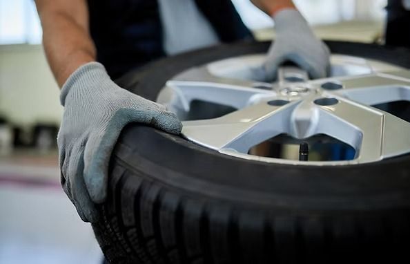 Person wearing gloves carrying a tire with a silver wheel rim. | Scottsdale Protech
